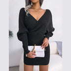 Woman holding a white quilted handbag while wearing a charcoal knit V-neck dress.
