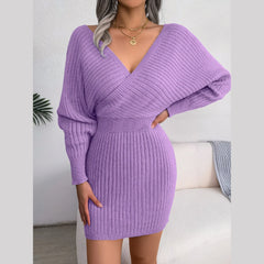 Woman posing in a purple knit mini dress with a V-neck and batwing sleeves.