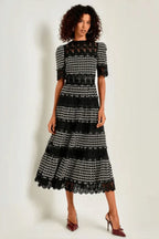 Woman wearing a black and white geometric print midi dress with lace details