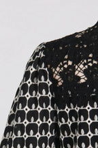 Close-up of the lace neckline and sleeve of a black and white geometric print midi dress
