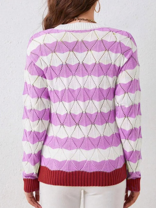 Back view of a woman wearing a purple and white striped knit sweater with an open-knit geometric pattern and contrast red cuffs and hem.