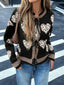 Woman wearing a black knit cardigan with a heart and leopard print pattern, tied at the front, paired with blue jeans.