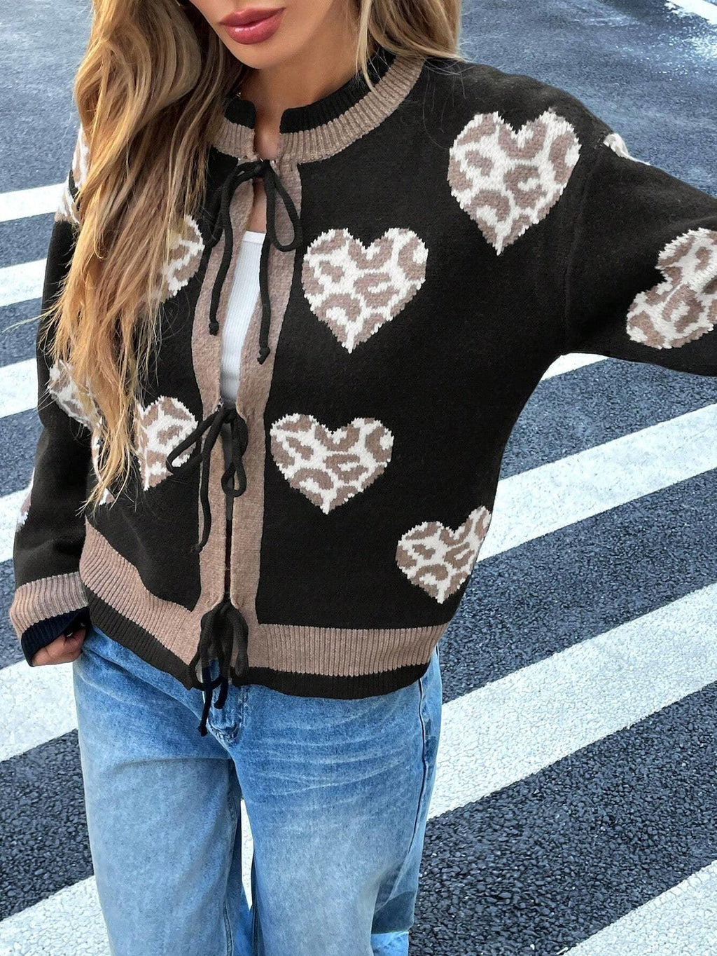 Close-up of a woman's torso wearing a black knit cardigan with a heart and leopard print pattern, tied at the front.