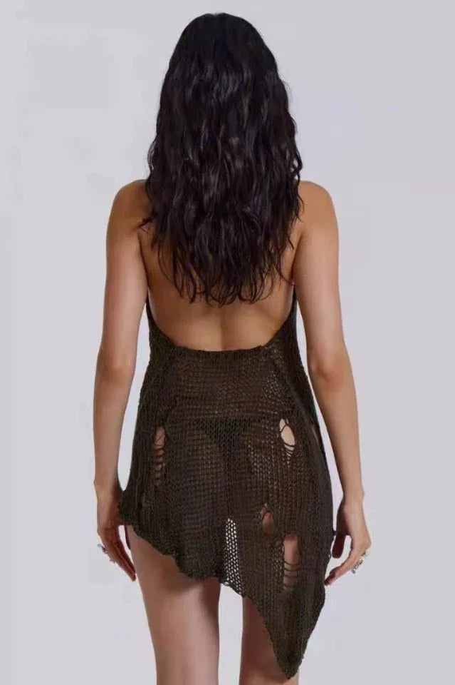 Back view of a model wearing a distressed knit halter mini dress, showcasing the open back and asymmetrical hem