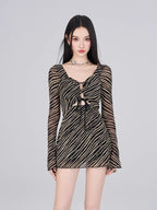 Model wearing a black and gold striped sheer mesh mini dress with a plunging V-neck and long bell sleeves.