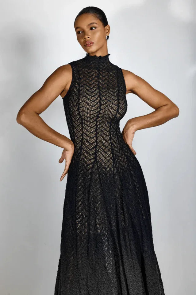 Woman posing in a black sleeveless mock neck midi dress with her hands on her hips