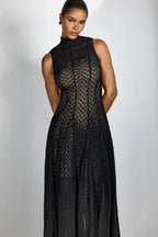 Close-up of a woman wearing a black chevron knit midi dress, hands behind her back