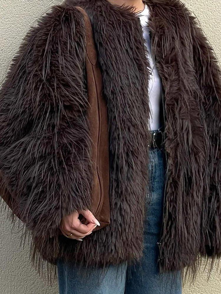 Close-up of a brown shaggy faux fur jacket worn over a white top and blue jeans.