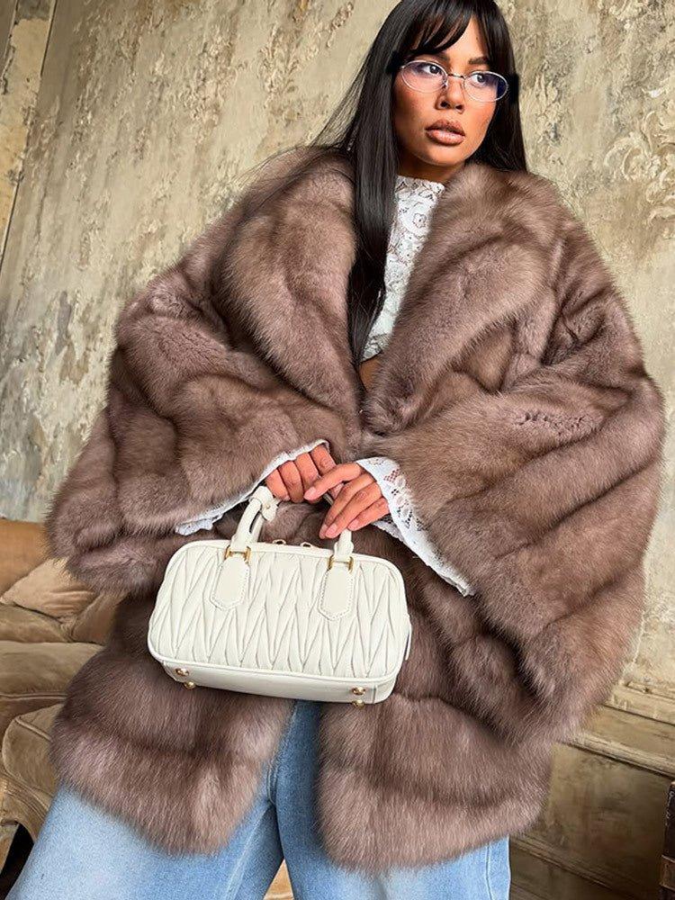 close-up of a woman wearing a brown oversized fur coat with wide lapels and long sleeves, holding a white handbag