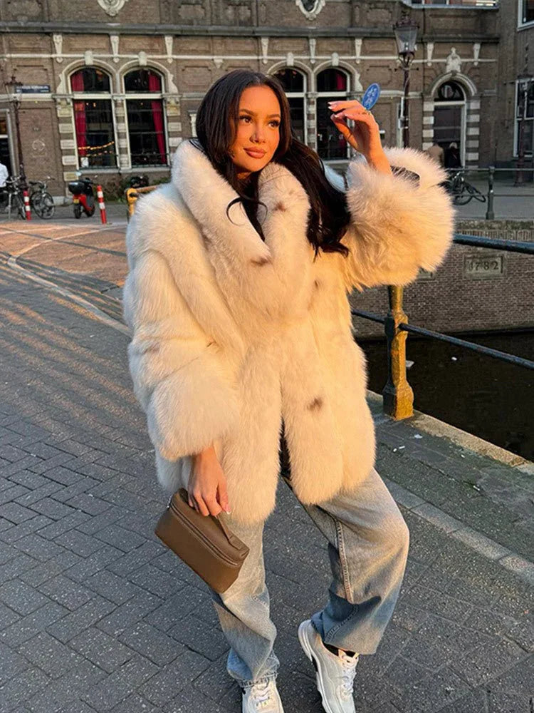 woman wearing a white faux fur coat with denim jeans and white sneakers