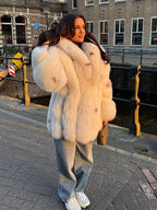 woman wearing a white faux fur coat with denim jeans and white sneakers