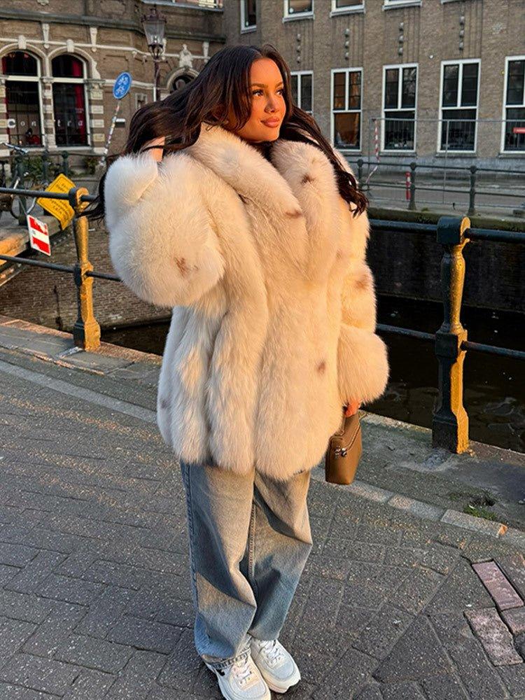 woman wearing a white faux fur coat with denim jeans and white sneakers