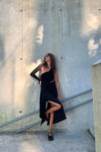 Model wearing black one-shoulder ribbed knit maxi dress with cut-out and high slit outdoors