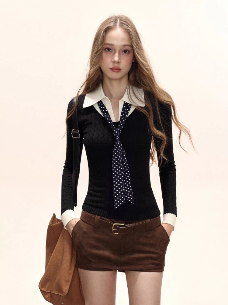 Woman wearing a black fitted knit sweater with a white collared shirt underneath and a navy polka dot tie, paired with brown shorts.