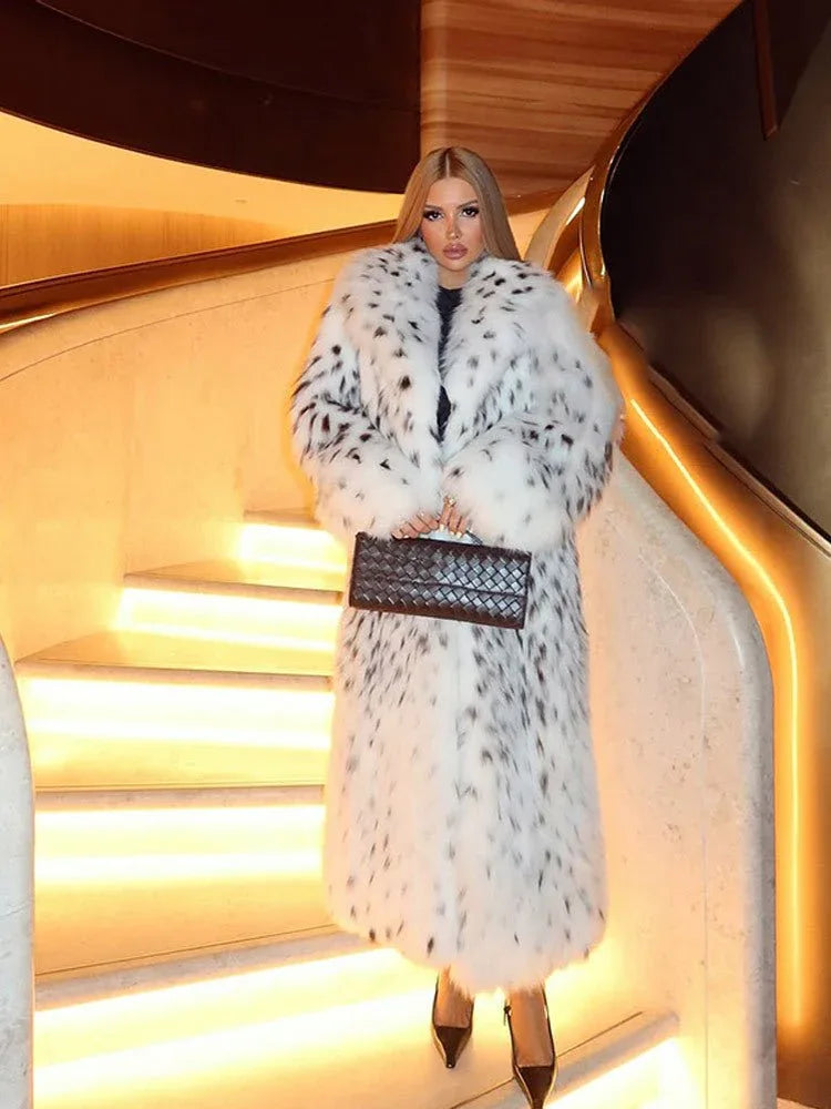 Woman in a long white and black spotted faux fur coat on a staircase holding a clutch.