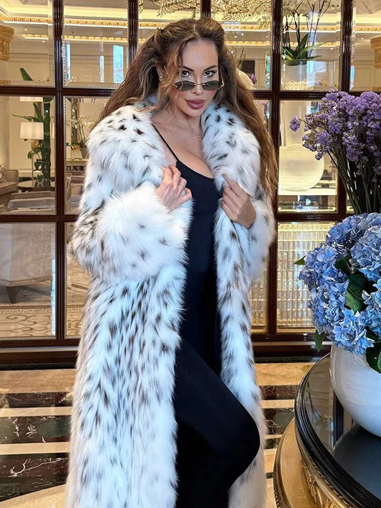 Woman wearing a long white and black spotted faux fur coat indoors. Main image