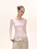 Side view of a model wearing a pink long-sleeved square neck top and a beige maxi skirt.