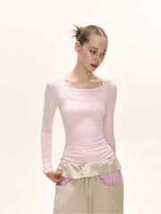 Side view of a model wearing a pink long-sleeved square neck top and a beige maxi skirt.