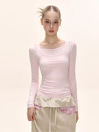 Close-up of a model wearing a pink long-sleeved square neck top and a beige maxi skirt.