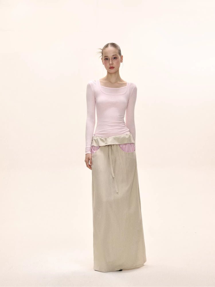 Full body shot of a model in a pink long-sleeved square neck top and a beige maxi skirt.