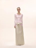 Full body shot of a model in a pink long-sleeved square neck top and a beige maxi skirt.