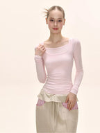 Model posing in a pink long-sleeved square neck top and a beige maxi skirt.