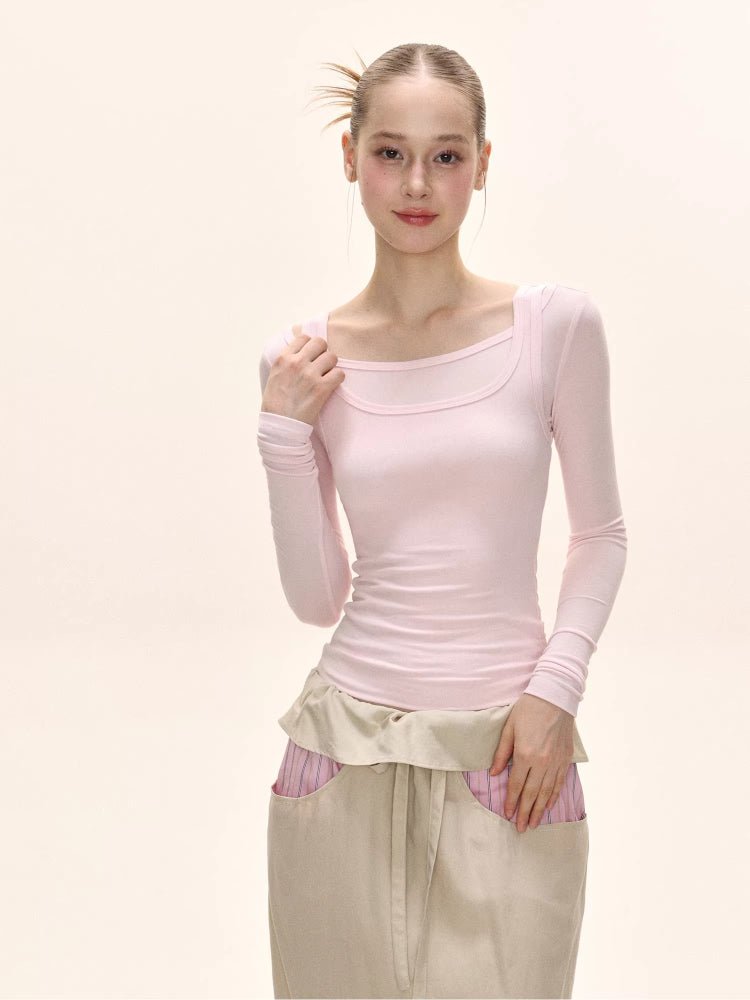 Model posing in a pink long-sleeved square neck top and a beige maxi skirt.