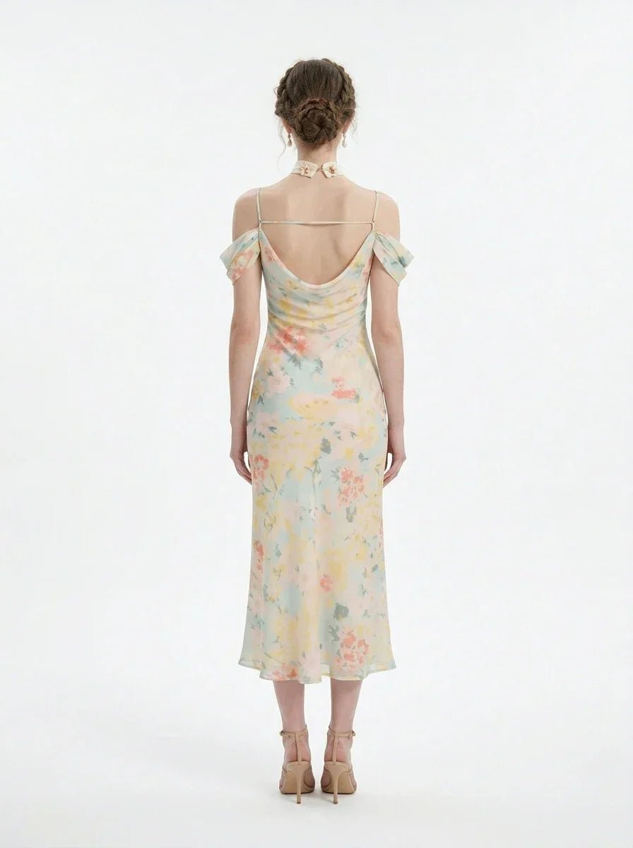 Back view of a woman wearing a floral print midi slip dress with off-the-shoulder sleeves and a cowl neckline, standing against a white background.