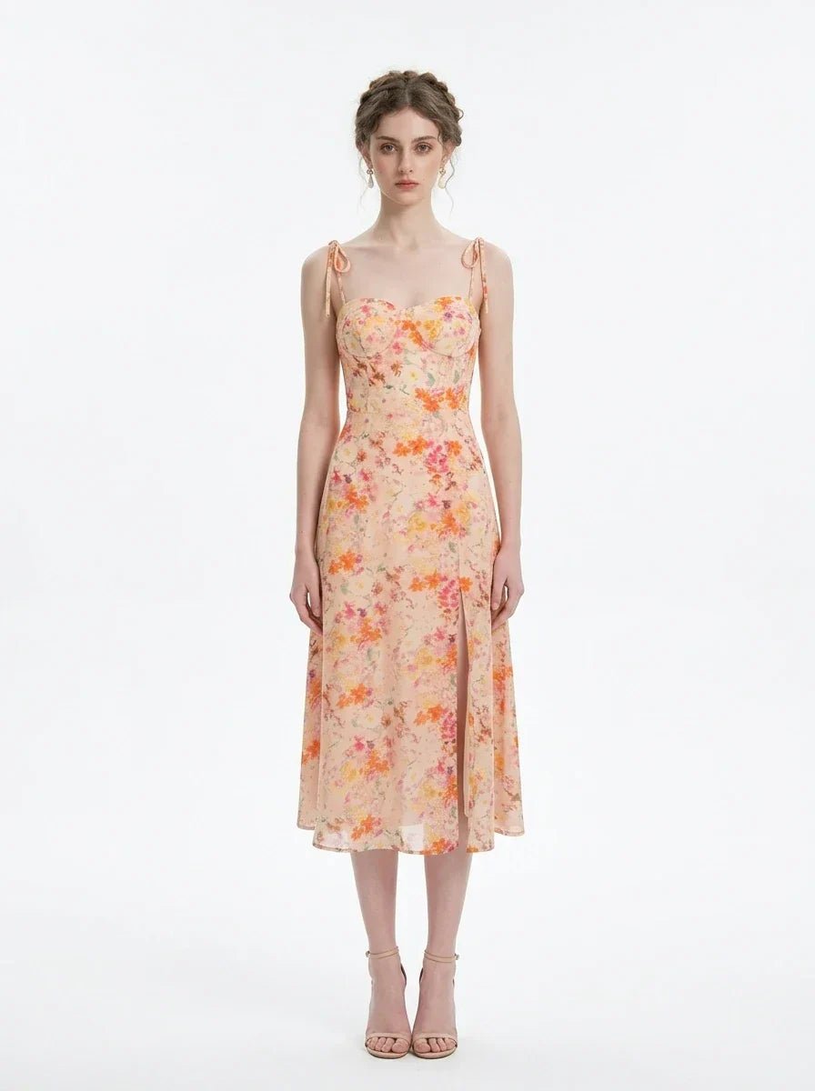 Model wearing a peach floral print midi dress with spaghetti straps and a thigh-high slit, standing against a white background.