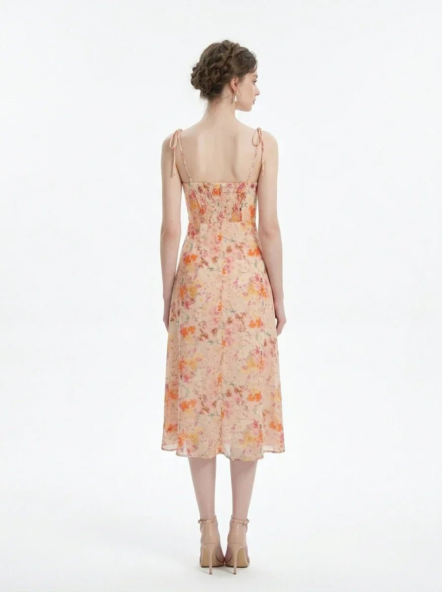 Back view of a peach floral print midi dress with spaghetti straps and a thigh-high slit, standing against a white background.