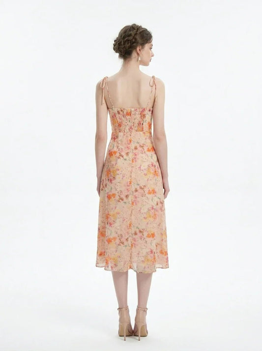Back view of a peach floral print midi dress with spaghetti straps and a thigh-high slit, standing against a white background.
