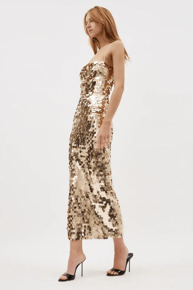 Side view of a woman in a gold sequined midi dress with spaghetti straps. Secondary image