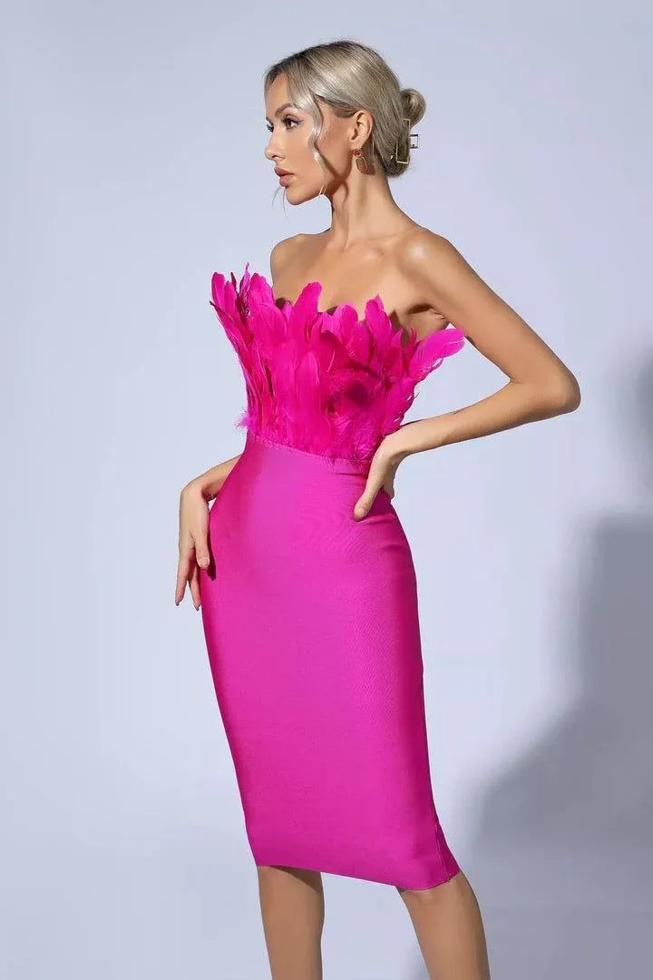 Woman in a hot pink strapless midi dress with a feather-trimmed bodice, posing against a white background.