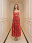 Woman standing in a hallway wearing a red floral print maxi dress with spaghetti straps and a sweetheart neckline.