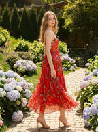 Woman walking in a garden wearing a red floral print maxi dress with spaghetti straps and a sweetheart neckline.