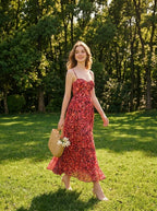 Woman in a red floral print maxi dress walking in a park