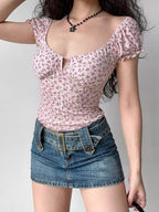 Full body shot of a woman wearing a pink floral print top and a denim skirt.