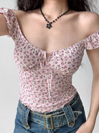 Woman wearing a pink floral print top with off-the-shoulder puff sleeves.