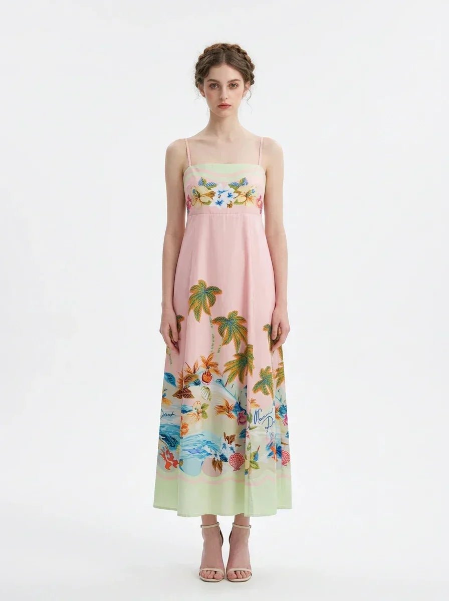 Full front view of a woman wearing a pink midi dress with a tropical print and spaghetti straps, standing against a white background.