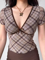 Detail of the v-neckline and bow on a plaid top.