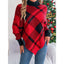 Woman wearing a red and black plaid turtleneck poncho with blue jeans.