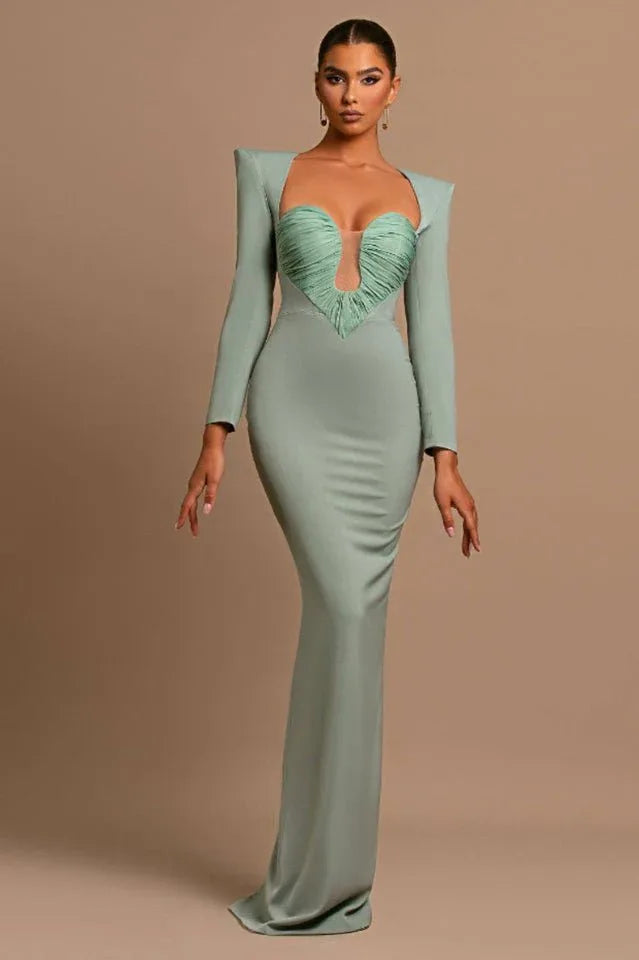 Woman wearing a sage green long-sleeved mermaid gown with a plunging ruched bodice and structured shoulders.
