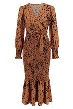 Product shot of a long-sleeved, brown and black animal print midi dress with a v-neck, tie waist, and ruffled hem.