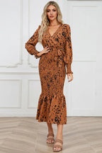 Front view of a woman modeling a long-sleeved, brown and black animal print midi dress with a v-neck, tie waist, and ruffled hem.