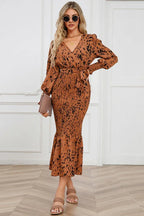 Woman wearing a long-sleeved, brown and black animal print midi dress with a v-neck, tie waist, and ruffled hem.