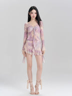 Full-length view of a woman in a purple and pink tie-dye mesh cover-up and matching bikini.
