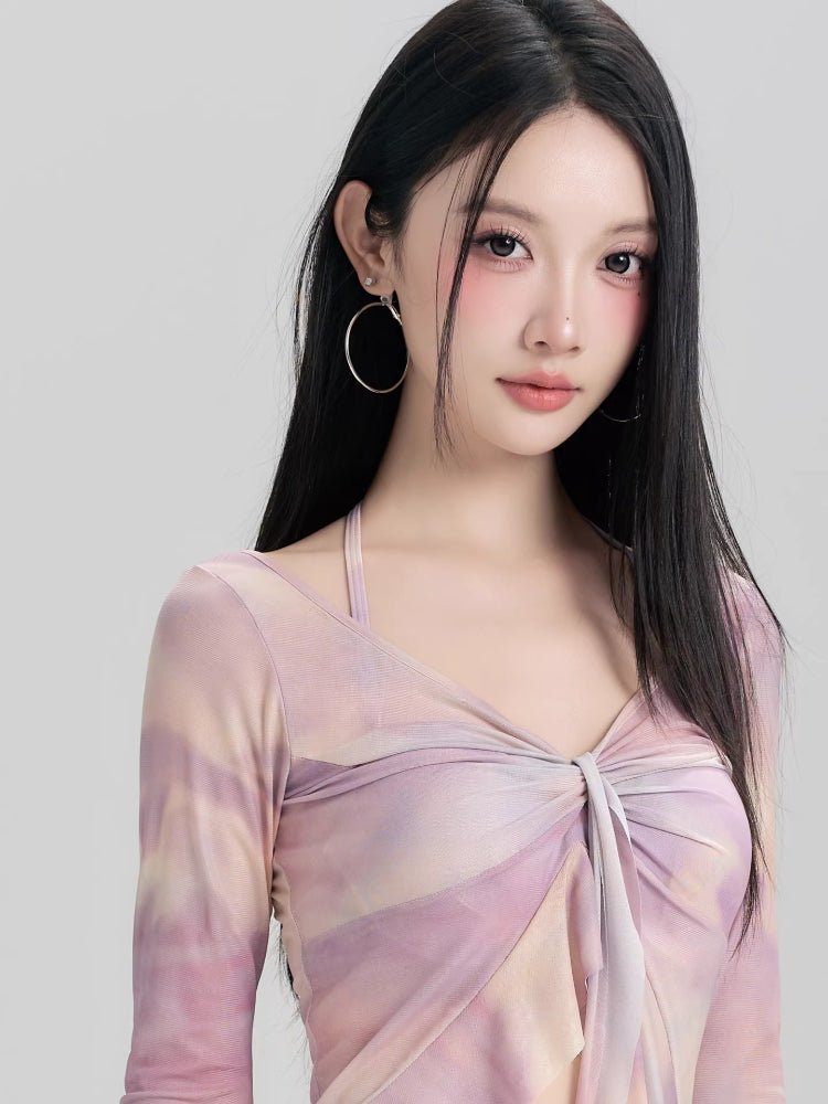 Close-up of a woman's face with makeup, wearing a purple and pink tie-dye mesh top.