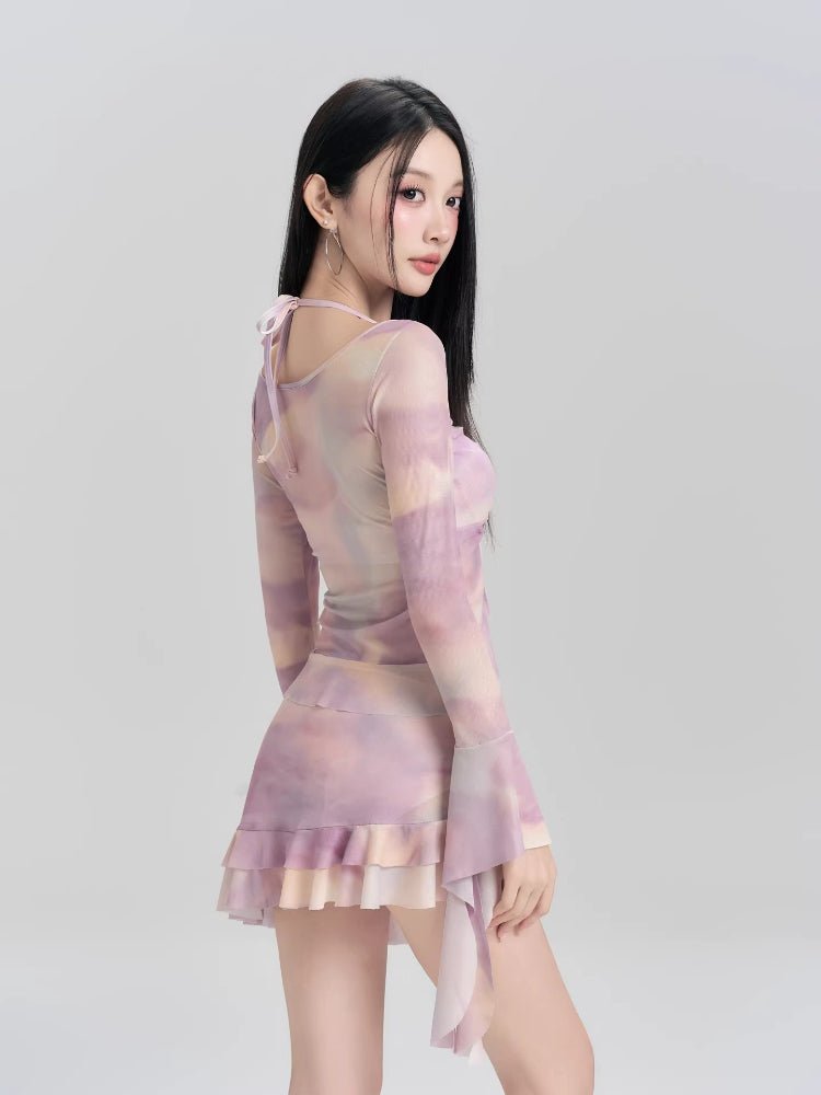 Woman from the side wearing a purple and pink tie-dye mesh cover-up with bell sleeves.
