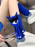 A person wearing blue socks with a blue and white eye and tentacle-like attachments, paired with white sneakers.
