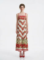 Woman wearing a floral print maxi dress with spaghetti straps, standing against a white background.